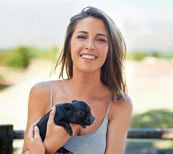 Portrait, outdoor and woman with a piglet, happy and summer with weekend break and bonding together. Face, person and girl with animal and pet with sunshine and cheerful with joy, ranch and smile.