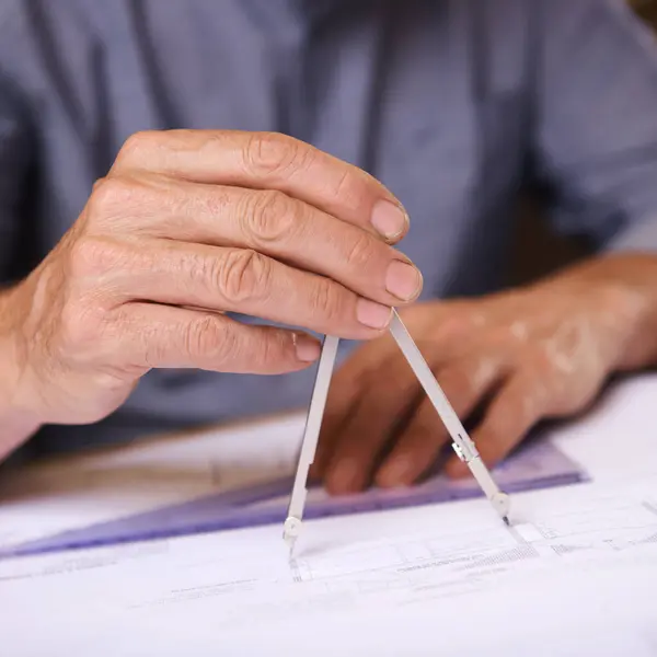 Hand, closeup of compass and architect drawing blueprint, construction and civil engineering with stationery. Drawing tools, equipment and person with floor plan for property or renovation project.