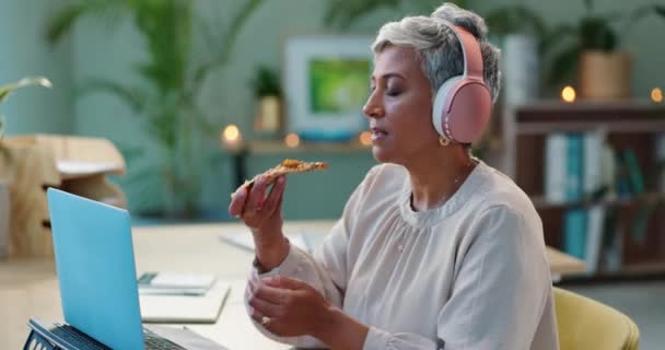 成熟したビジネス女性 ラップトップ ヘッドフォンは オフィスの夜にピザ デスク 栄養と昼食休憩のためのものです ジャーナリスト コンピュータ ポッドキャスト ペッパーニー — ストック動画