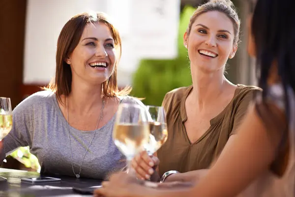 Friends, wine and women drinking at cafe with laughing, bonding and relax outdoor in city for celebration. People, face and happy with alcohol at restaurant for social gathering, funny gossip or joke.