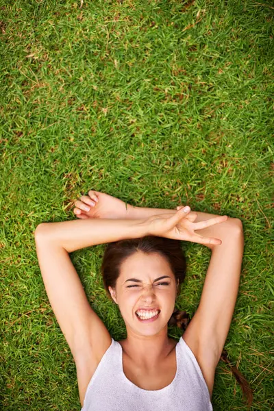 Woman, portrait and top view on grass for relax with funny face, peace sign and weekend break in summer. Young person, happy and confident on lawn, garden or backyard of home for fresh air on mockup.