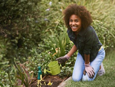 Kadın, baharda, açık havada ya da çimenlerde bitkilere gülümseyen bahçe ve su tenekeleri. Kız, Afrikalı ve arka bahçedeki ekolojinin gelişimi, gelişimi ya da doğası için dünyadan memnun..