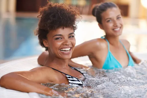 Women, friends and happy in portrait in jacuzzi to relax, self care and pamper day at spa for wellness and healing. Water, bubbles and hot tub for detox and stress relief, friendship date and bonding.