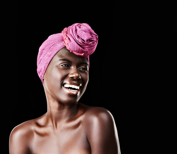 Black woman, head wrap and laugh with natural beauty, skincare and cosmetics in studio. Traditional, turban and African style with wellness and skin glow in makeup with confidence and dark background.