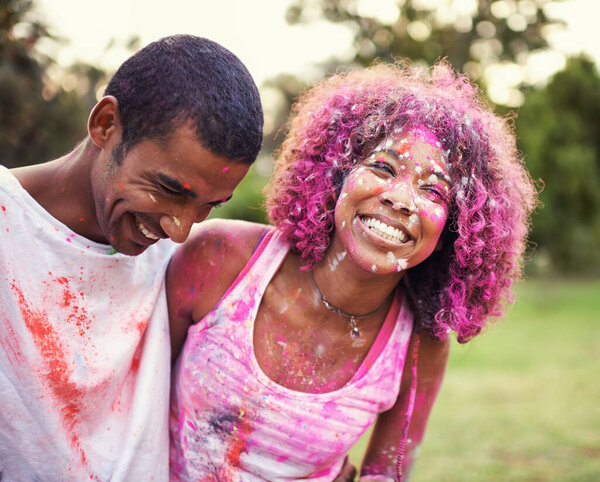 Happy, powder paint and couple of friends outdoor with Holi festival and colorful event with smile. Celebration, love and excited in nature with African people and crazy color dust for party together.