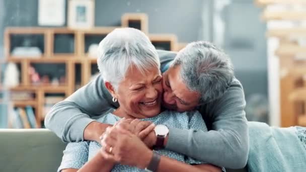 シニアカップル 抱擁し 愛で面白い記憶のために頬にキスしてソファーに顔を合わせます 高齢者女性と家のソファー 接続または退職によって後ろから抱擁するために幸せ — ストック動画