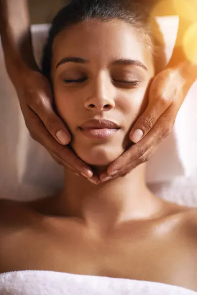 Woman, spa and facial for massage on face with hands and care for lens flare, wellness and beauty treatment. Above, towel and african female person with skincare and relax at hotel with skin glow.