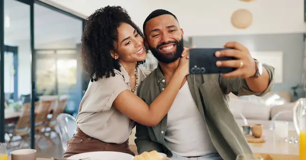Home, selfie and couple with love, funny and smile with happiness and social media in a living room. Apartment, man and woman in a lounge, profile picture and humor with laughing and bonding together.