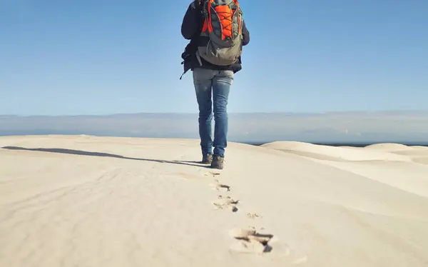 Walking, sand dunes or legs of person for adventure, desert landscape and travel for holiday vacation trip. Back view, hiker and nomad explorer hiking in Sahara terrain, outdoor and dry climate.