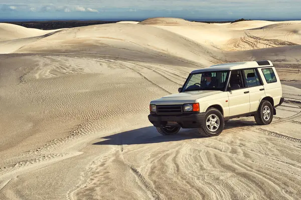Car, desert and driving with travel and transportation outdoor, off road vehicle for sand dunes and journey on vacation. Van, 4x4 or SUV with adventure, explore destination and tourism in Dubai.