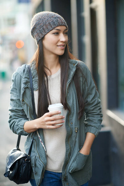 Woman, fashion and denim with coffee, travel and city street or background for style. Asian student, beanie and jacket in cape town with winter, cold and adventure with urban holiday for confidence.