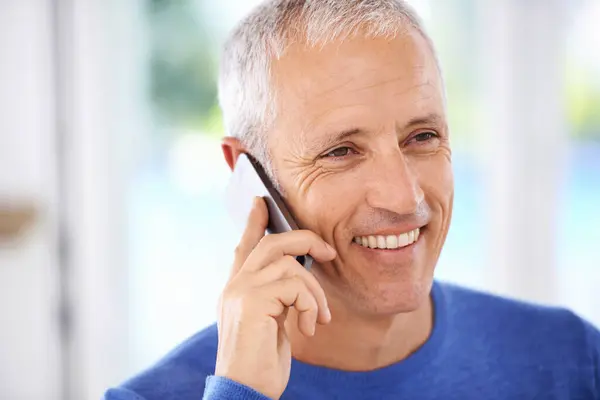 Senior, man and face with phone call in home with laughing for funny conversation, discussion and mobile chat. Elderly, person and happy with smartphone for talking, comic joke and mockup space.