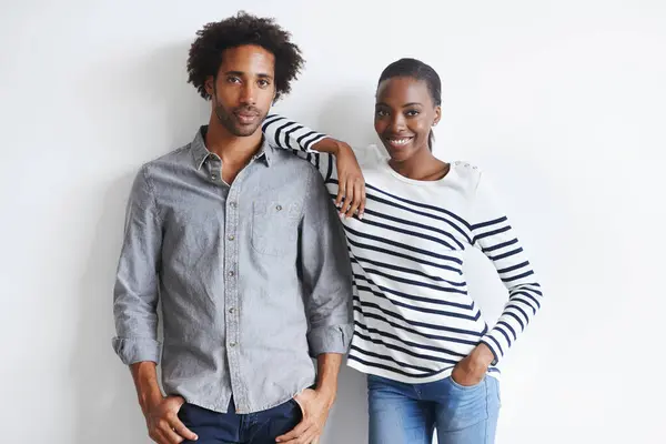 Couple, happy and portrait by white wall in fashion with confidence, casual style and model aesthetic. Black woman, and face of man with trendy apparel, edgy clothes and smile with bonding and relax.