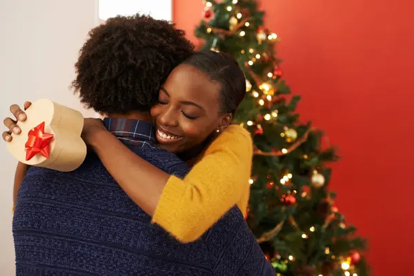 クリスマス プレゼント ブラックカップルは ボックスでハグしたり お祝いの休暇や幸せで休暇にサプライズを開いたりします 抱擁し 女性と男性は結婚の愛と優しさで家で贈り物を提供します — ストック写真