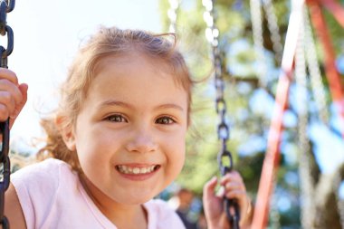 Kız, çocuk ve portre, Güney Afrika 'da mutlulukla, sıhhatle ve açık havada parkta oynadığı için salıncakta. Çocuk, oyun parkında yüzün ve gülümse eğlence, sağlıklı çocukluk gelişimi ve özgürlük için..