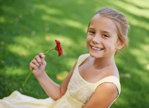 Child, portrait and smile with flower in garden for summer relaxing on holiday vacation, environment or plants. Female person, girl and face on backyard grass in Australia for spring, floral or happy.