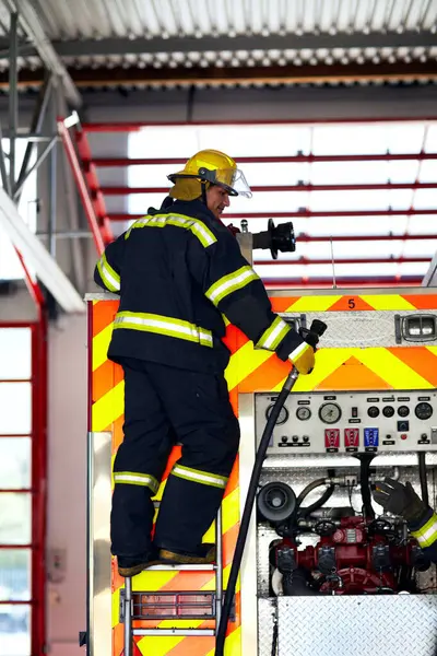 Firefighter, ladder and safety worker with hose truck at a fire station with emergency service employee. Uniform, firetruck and helmet of a fireman ready for rescue working with equipment at a job.