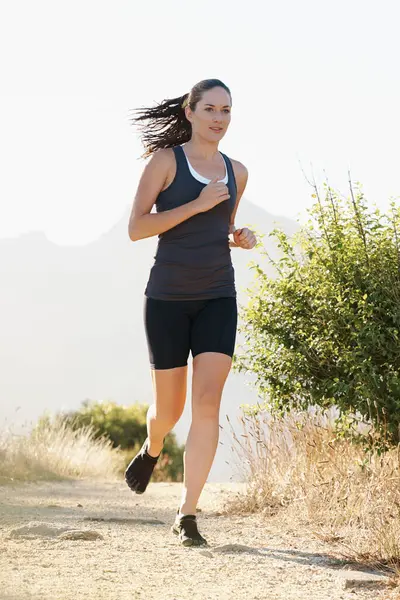 Runner, woman and running on trail with fitness for sport, training or exercise for competition on mountain. Athlete, person or marathon with wellness, challenge or cardio for healthy body in Denmark.
