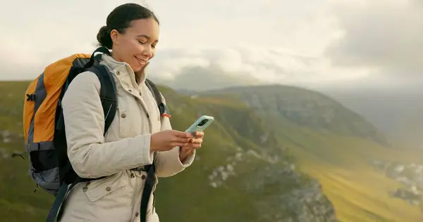 Woman hiking and travel on mountains with phone for social media update, location search and outdoor internet. Young influencer with backpack and mobile app for trekking results or progress on a hill.