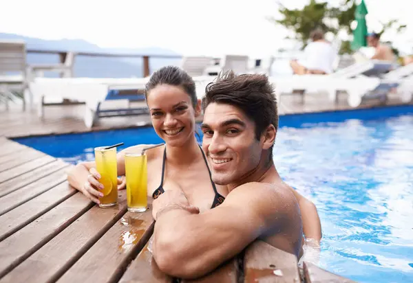 Swimming pool, cocktails and couple with holiday, portrait and weekend break with vacation and honeymoon. Sunshine, man or woman with tropical drink and wet with luxury or summer with love or alcohol.
