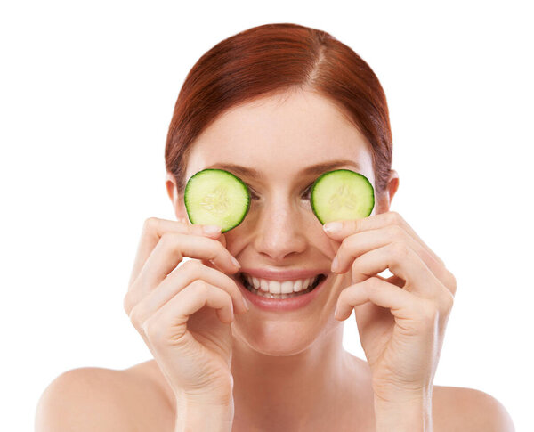 Woman, smile and cucumber in studio for skincare with natural beauty, shine and hydration benefit on white background. Face, cosmetics and hand with fruit for vitamin c, dermatology and self care.