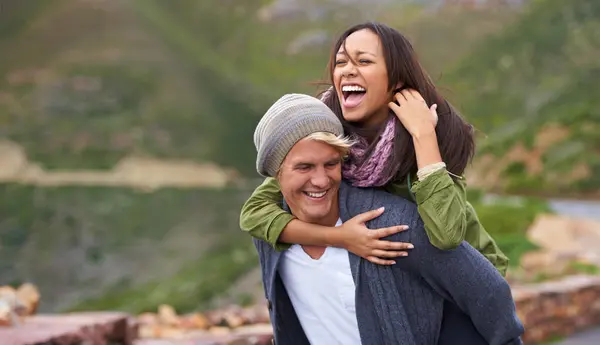 Smile, couple and piggyback in nature, hiking and travel together on adventure for date on holiday. Funny, outdoor and man carrying woman, trekking and interracial people laughing in the countryside.