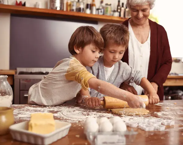 キッチンで焼くおばあちゃん 子供たちは 家族の家で一緒に絆を深めています おばあちゃん 子供たち 小麦粉で料理したり ピンを転がしたり テーブルで生地を教えたり — ストック写真