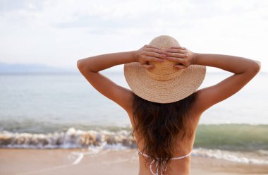 Yaz tatilinde ya da Bali 'de rahatlamak için seyahat macerasına atılan şapkalar, eller havaya ya da kadınlar denize. Temiz hava, özgürlük ya da minnettarlık için kumsalda kollarını açmış bir kadın ya da sırt, nefes al..