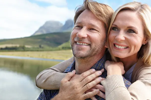 Lake, smile and couple at countryside in summer for weekend vacation, holiday and bonding together. Man, woman and happy with embrace in nature for adventure, travel and tourism outdoors in Europe.