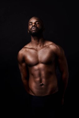 Siyah adam, model ve kaslı. Stüdyonun arka planında fitness, moda veya erkeksi bir figür var. Çekici Afrikalı, erkek ya da vücut geliştirici. Gözleri karın kasları için kapalı ya da uzayda güçlü..