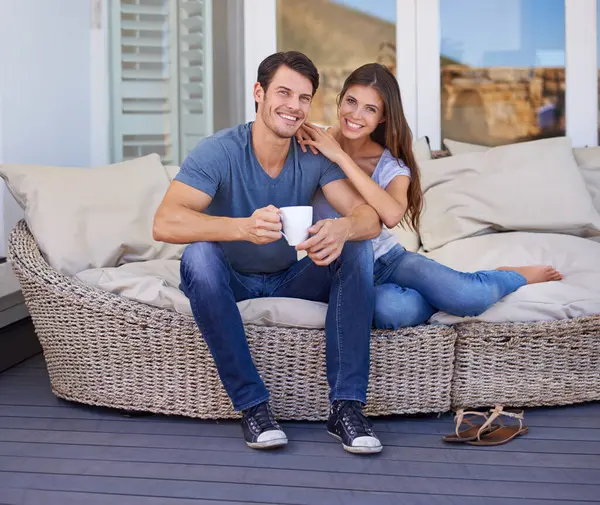 Coffee, portrait and couple on outdoor sofa for conversation, bonding or love on patio in morning. Happy, talking and young man and woman laughing and drinking cappuccino, latte or espresso at home