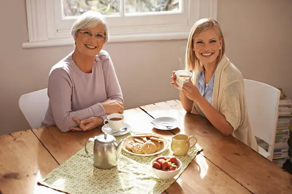 肖像画 幸せな女性と高齢の母親は 朝食で紅茶を飲んで 家で絆を深め 微笑んでいる シニアママと大人のテーブルでコーヒーカップ 食べ物や家族一緒に自宅でビスケットを食べる — ストック写真