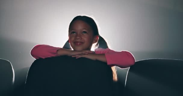 小女孩 在电影院里笑着看电影 开心而孤独的坐着空座位 孩子在电影院的电影 娱乐和明亮的灯光与座位在夜间 — 图库视频影像