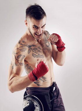 Yumruk, MMA ve dövüş sanatları pozu için kızgın erkek dövüşçü, boks ve beyaz arka planda çılgın bir ifade. Sargılar, eller ve sporcular ve insan kickboksörü, stüdyo ve çarpışma sporları eğitimi.