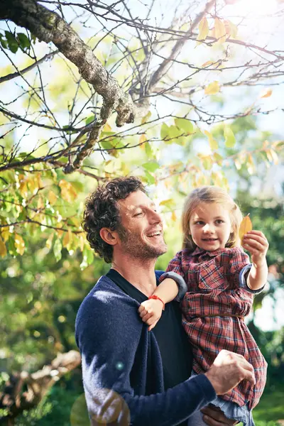 Father, daughter and happiness in garden in autumn with trees, leaves and curious for ecosystem and environment. Family, man and girl child with smile in backyard of home for bonding, nature or relax.