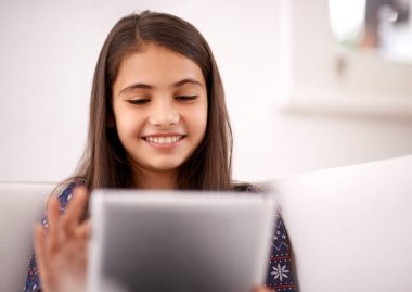 Rahatla, kanepe ya da tabletli mutlu çocuk film sitesinde oyun oynamak ya da video izlemek için. Eğitim, çevrimiçi ve evde uygulama veya kitap okuyacak teknolojiye sahip bir kız..