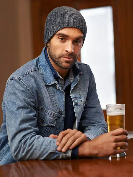 Portrait, beer and male person thinking at pub, drinks and restaurant for entertainment. Pensive, alcohol and bar for thoughtful or social for relax, smile and beanie for cold weather in England.