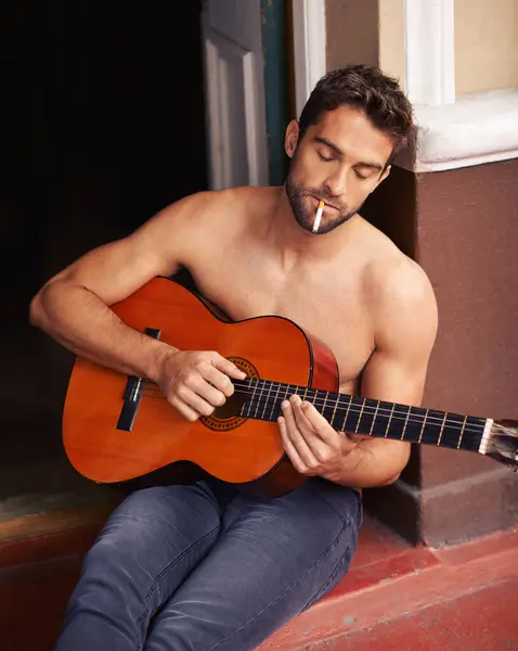 Guy, guitar or home to relax as inspiration, thinking or idea of future, smoking or vision on break. Man, shirtless or cigarette as musical instrument to remember, chill or rest at weekend getaway.