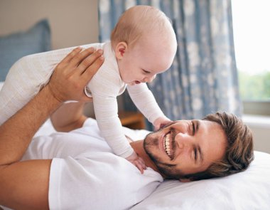 Baba, yatakta gülüyor ve kız bebek yatak odasında birlikte oynuyorlar. Mutluluk, çocukluk gelişimi, ebeveynlik ve sabah eğlencesi için neşeli adam ve kız.