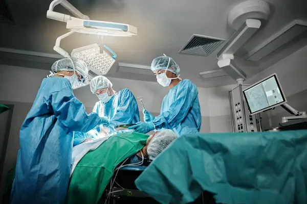 Healthcare, surgery and doctors with patient for emergency medical procedure in theater. Hospital, lights and surgical team for operation on person together in ICU, professional support and help