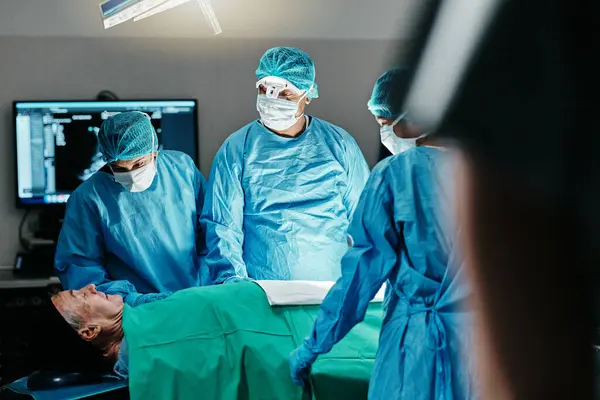 Medical, surgery or doctors in operating room with theater patient or trauma unit for anatomy emergency. Healthcare, support and surgeon team consulting sick man at hospital with empathy and comfort.