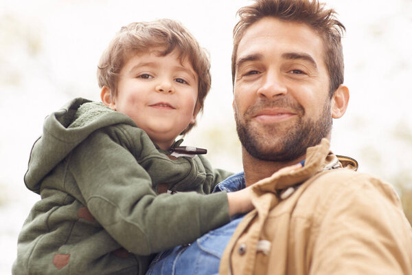 Father, child and portrait smile in nature for relax bonding on weekend holiday, vacation or connection. Male person, boy and face for outdoor together for parents love or traveling, holding or care.
