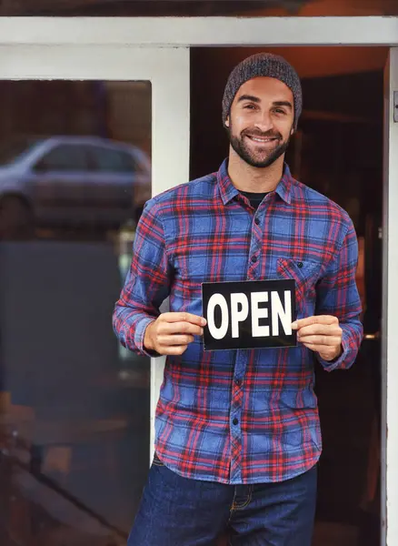 Small business, cafe and portrait of man with sign at entrance of restaurant with smile. Open, confidence and entrepreneur at coffee shop with career in service, hospitality and happiness at door.