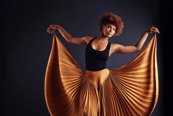 Performance, theatre and portrait of black woman dancing, creative and art of body, moving and passion. Dark background, studio and girl with pride, confident and female person with balance and stage.