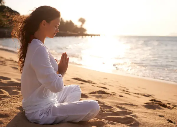 Beach, meditation or woman with prayer hands in nature at sunset for peace, zen or mental health wellness. Spiritual, balance or person at the ocean for energy, breathing or holistic self care at sea.