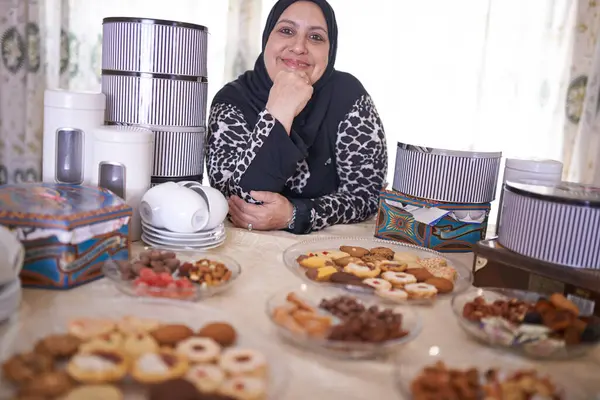 イフタールのための陽気で笑顔とダイニングテーブルと家で成熟した女性 イスラムと食べ物 イスラム教徒の人 クッキーデザートと喜び イードムバラク 宗教と自宅で断食のための祝賀 — ストック写真