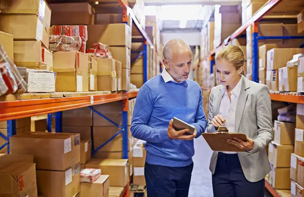 Tablet, checklist and business people in distribution warehouse for logistics, supply chain and cardboard box. Package, ecommerce and employees with technology for shipping, cargo and stock taking.