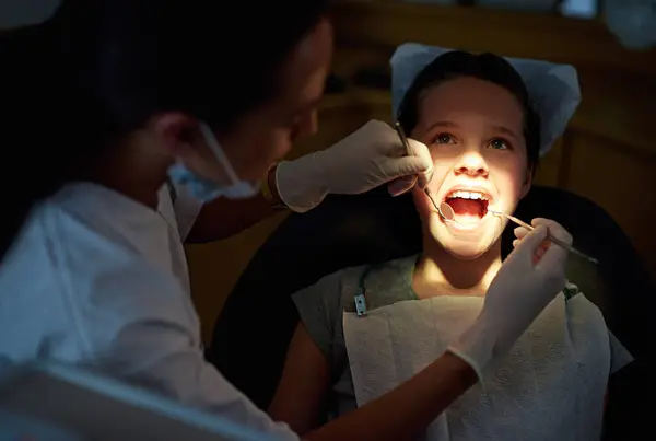 ミラーまたは口腔検査のための歯科医 歯の洞窟またはガム病 細菌または検索のための少女 小児歯科またはクリーニングのための軽い 装置または用具が付いている口腔ケア 健康または医者 — ストック写真