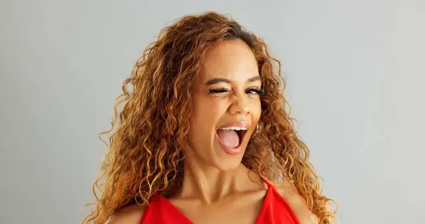 stock image Happy woman person, wink and laughing in studio, excited and flirt on grey background. Cheerful, joyful and smile on female model face, friendly and natural with curly hair of fun African Lady.