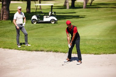 Erkekler, yaz günü spor, sağlık ve spor için dışarıda golf oynayın. Atışa hazır olun. Millet, 9 delikli aktif giysi oyununda sığınaktaki doğal çim topunda antrenman ve rekabet.